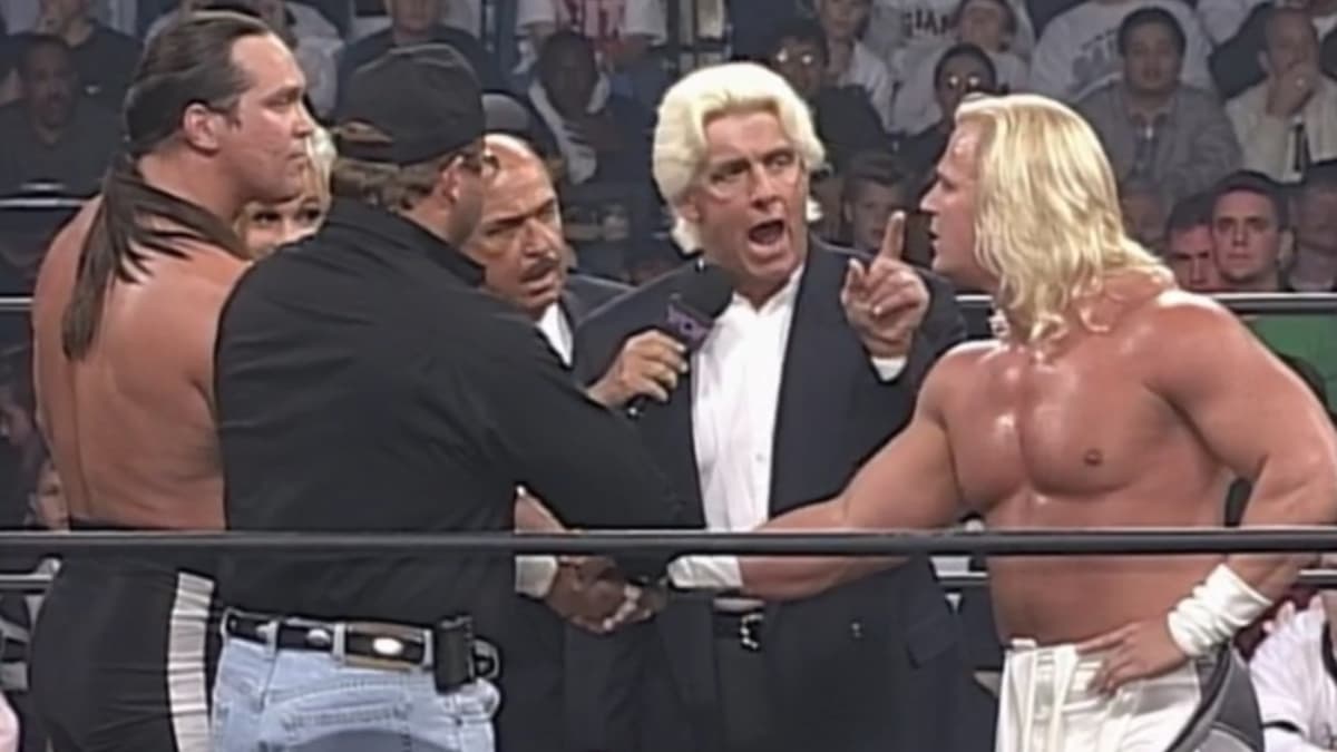 Jeff Jarrett shaking Steve McMichael's hand as Ric Flair speaks to him