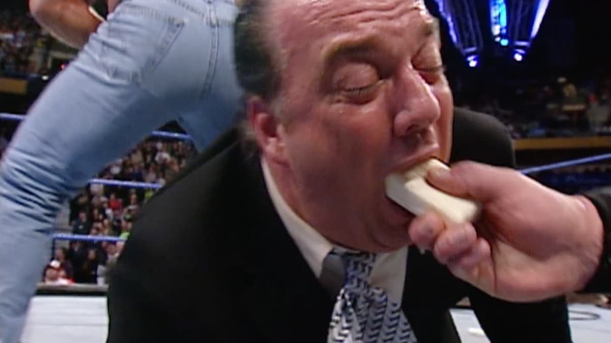Paul Heyman eating a bar of soap being held by John Cena
