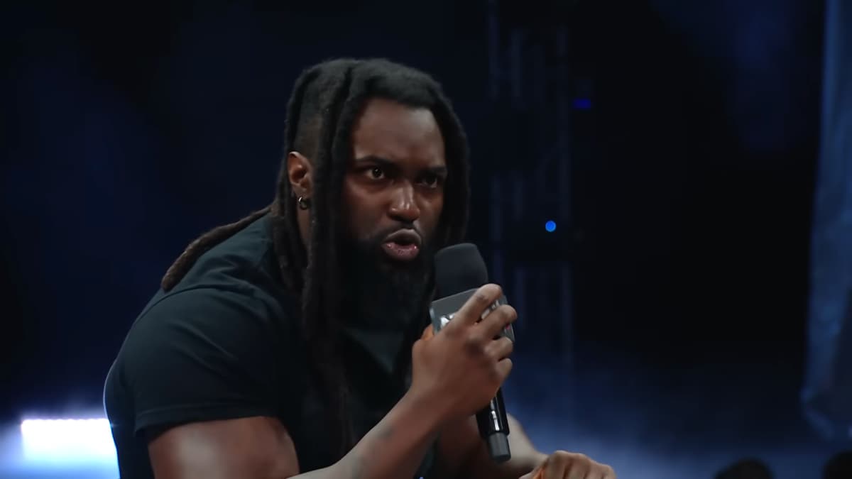 Keanu Carver speaks through a microphone at a WWE NXT event