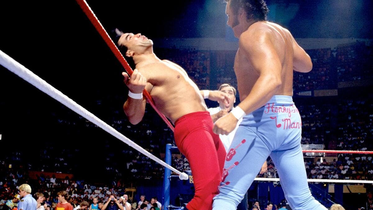 Ricky Steamboat on the ropes in pain as The Honky Tonk Man looks on next to him