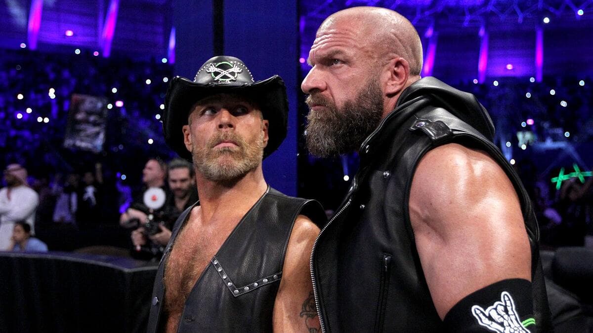 Triple H and Shawn Michaels in leather vests standing outside the ring