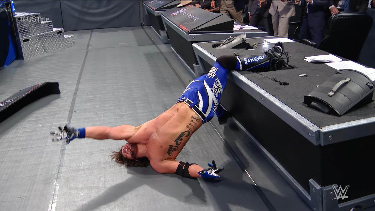 AJ Styles with his foot in the announce table
