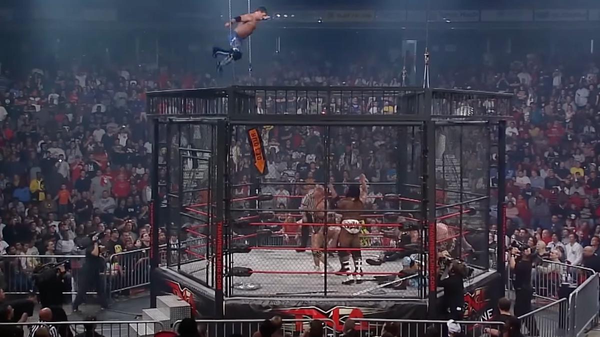 AJ Styles jumping through the top of the Lethal Lockdown cage onto Kurt Angle, Scott Steiner and Booker T who are stood in the ring