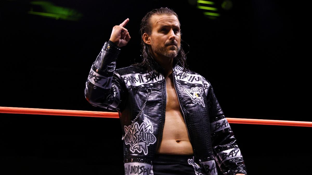 Adam Cole posing in his entrance jacket in an AEW ring