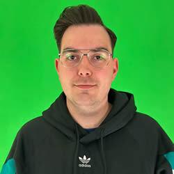 Aidan Gibbons smiling in front of a green screen in an Adidas hoodie 