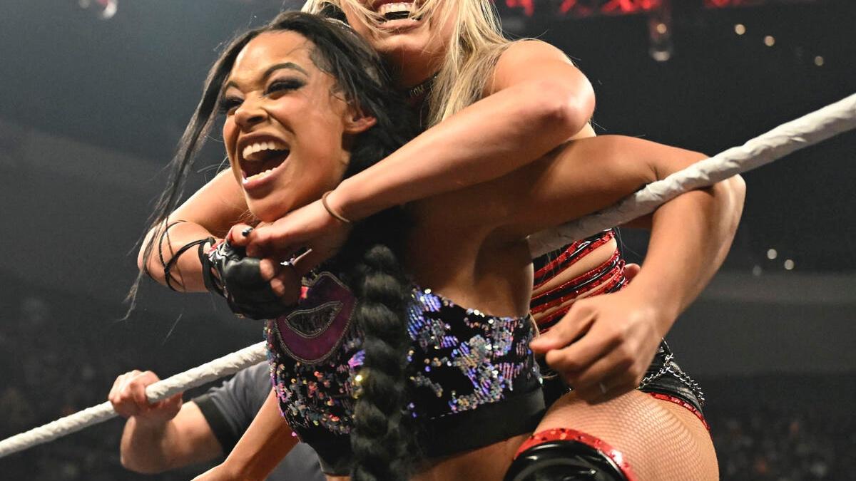 Bianca Belair in the ropes with Liv Morgan's arms wrapped around her 