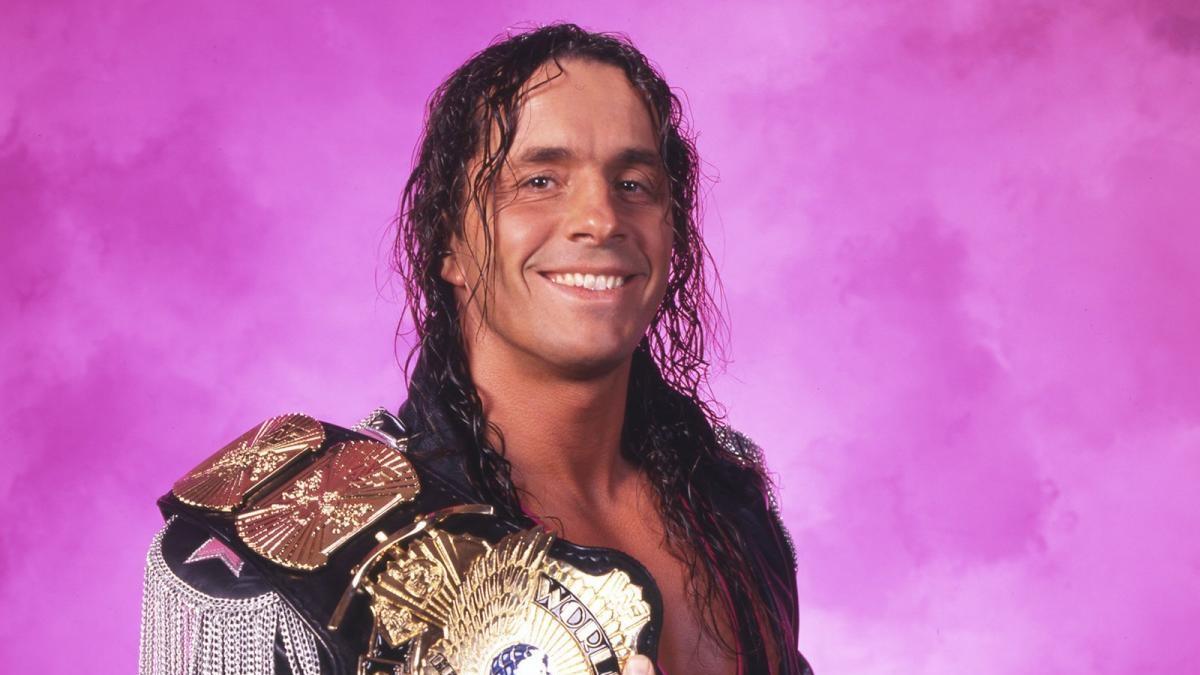 Bret Hart smiles and holds the WWE Title belt while posing for a portrait photo during the mid-90s