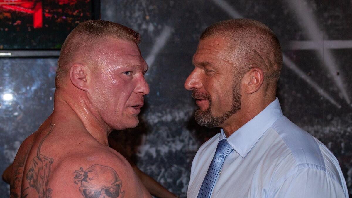 Brock Lesnar and Triple H look at each other while backstage in the Gorilla Position at a WWE show in 2015