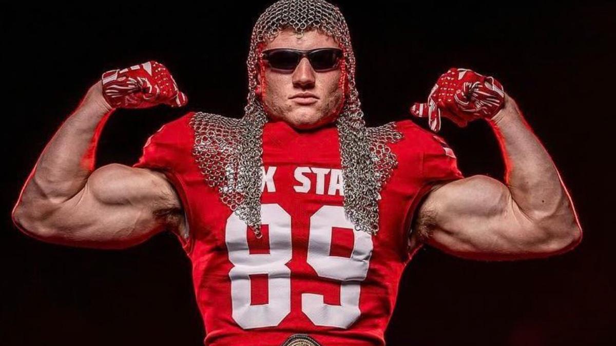 Scott Steiner's son Brock poses wearing a football jersey, his father's chainmail headgear and dark sunglasses