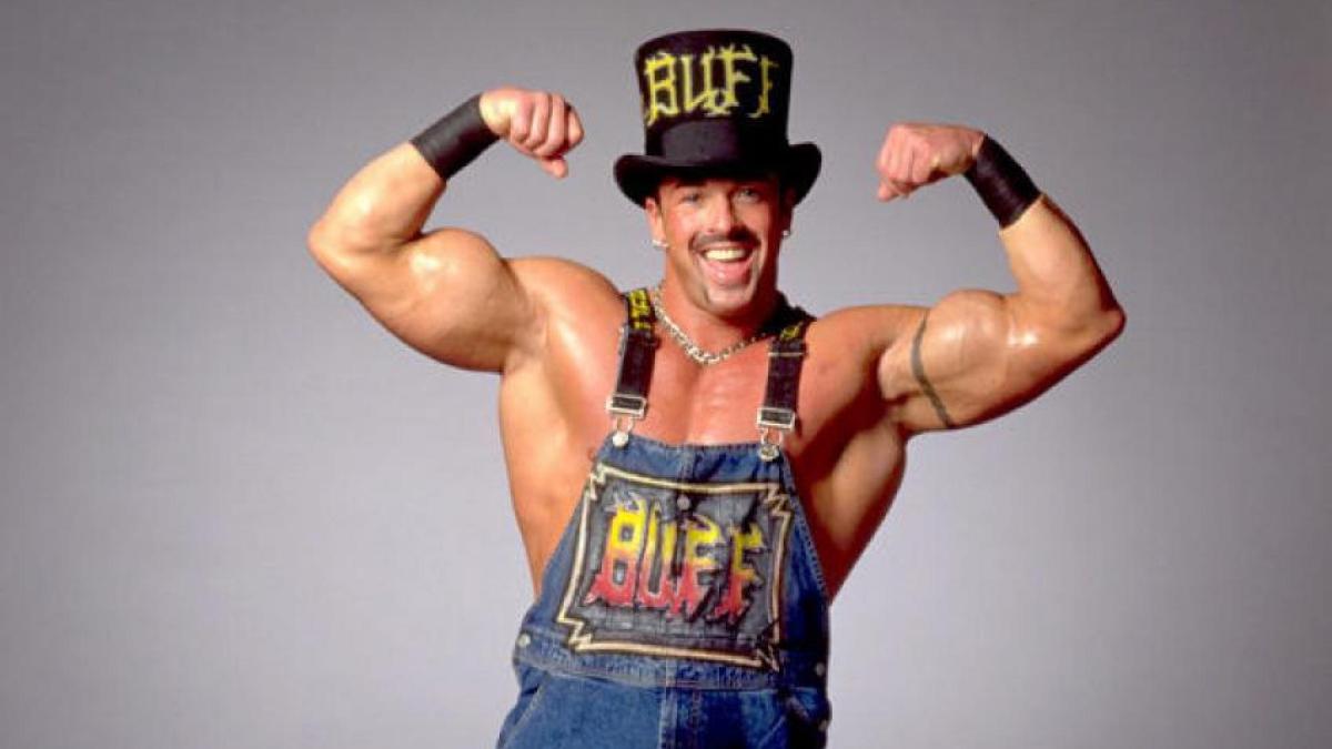 Buff Bagwell posing and smiling in customised dungarees and a top hat