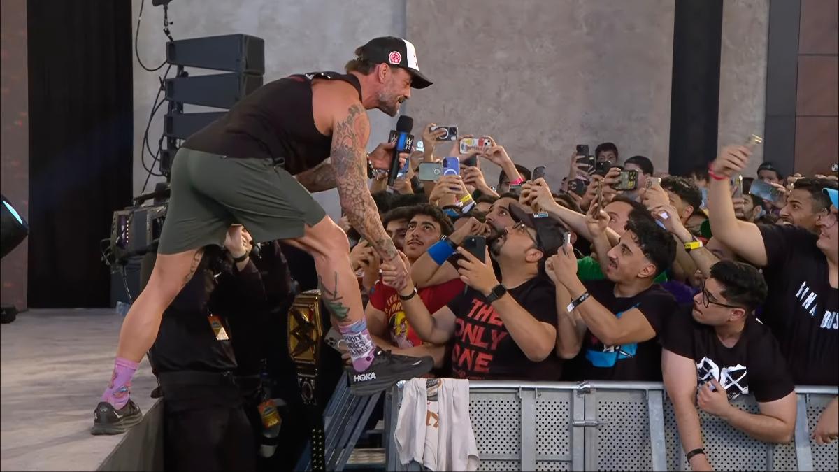 CM Punk shaking a man's hand while stepping on a barricade