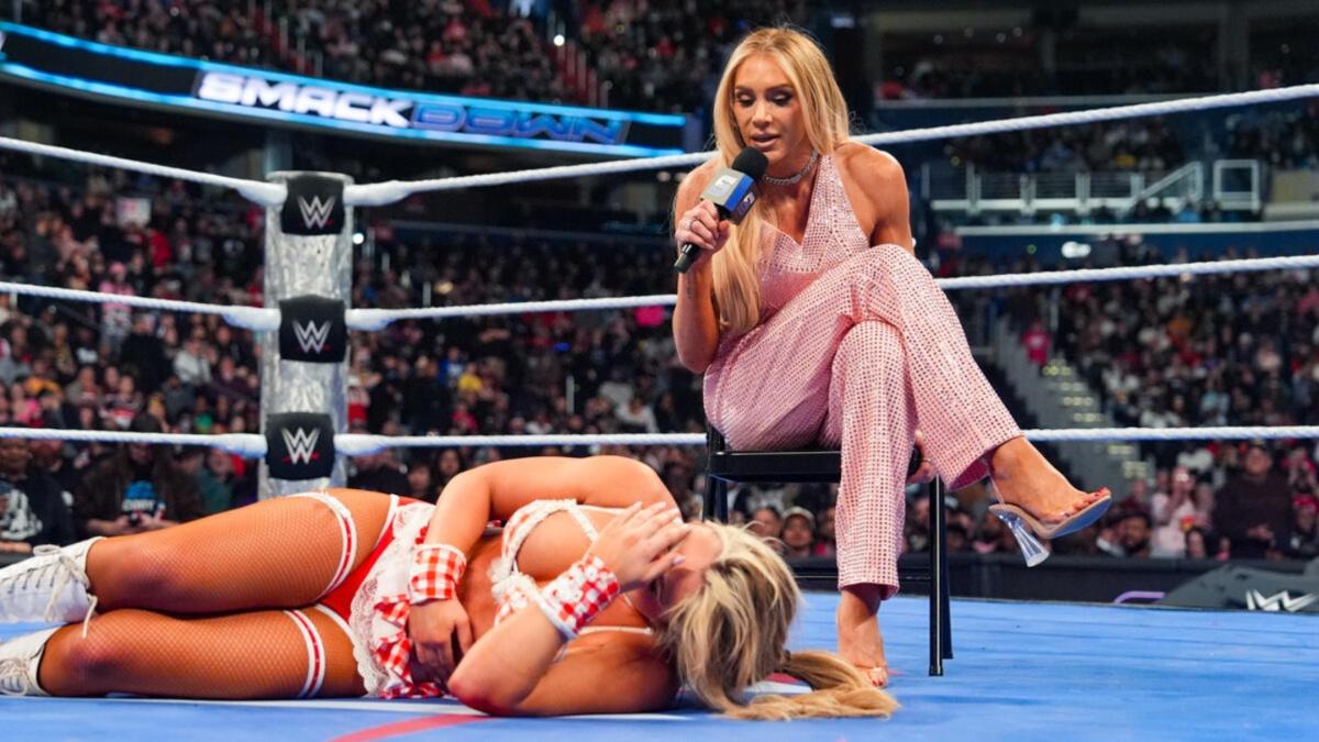 Charlotte Flair sitting in a chair talking to a prone Tiffany Stratton 