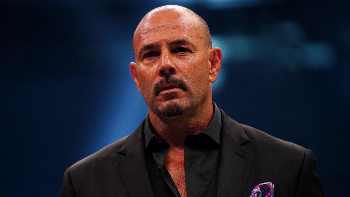 Chavo Guerrero in a black suit and shirt looking disappointed