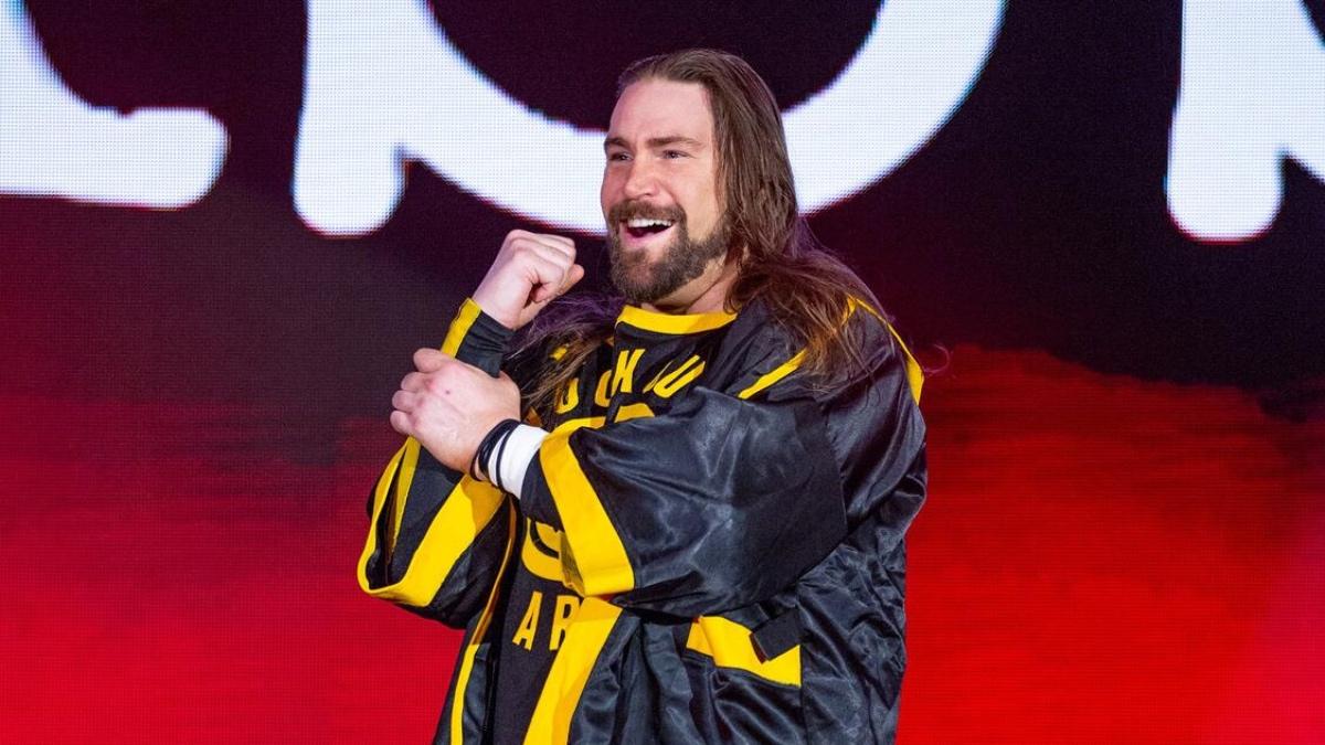 Chris Hero as Kassius Ohno smiling in yellow and black attire on WWE NXT