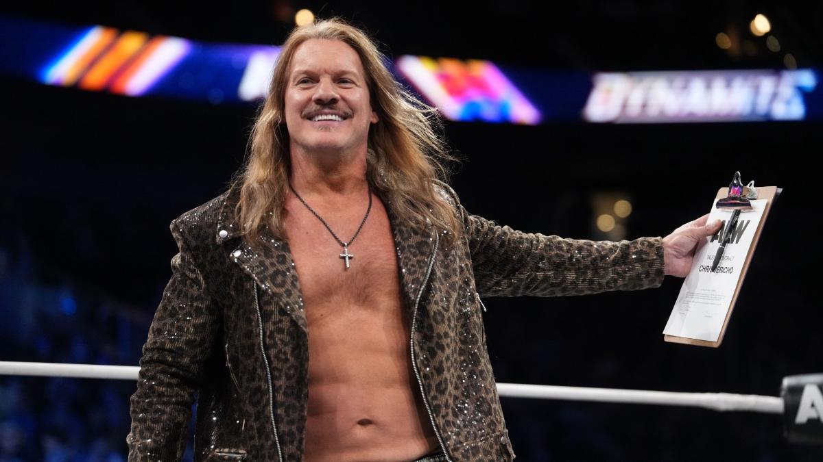 Chris Jericho holding an AEW contract while wearing a sparkly jacket 