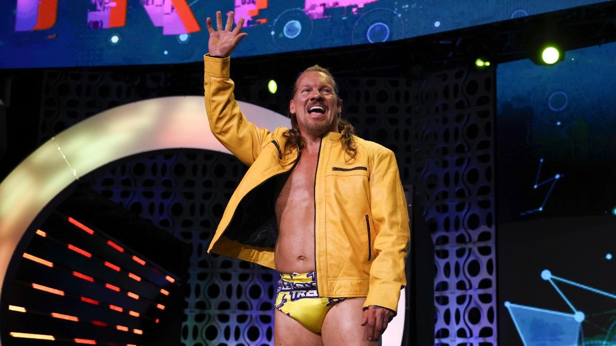 Chris Jericho wearing a yellow leather jacket and yellow trunks waving