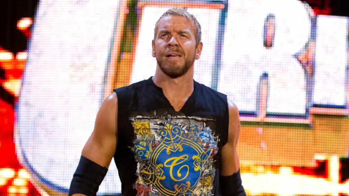 Christian Cage in a sleeveless top standing with a bright WWE LED screen in the background.