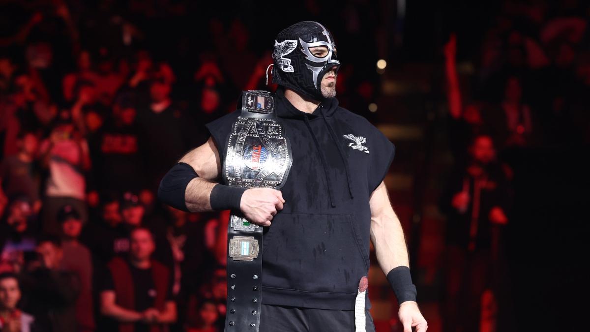 Claudio Castagnoli with the CMLL World Heavyweight Title over his shoulder wearing a Death Riders luchador mask