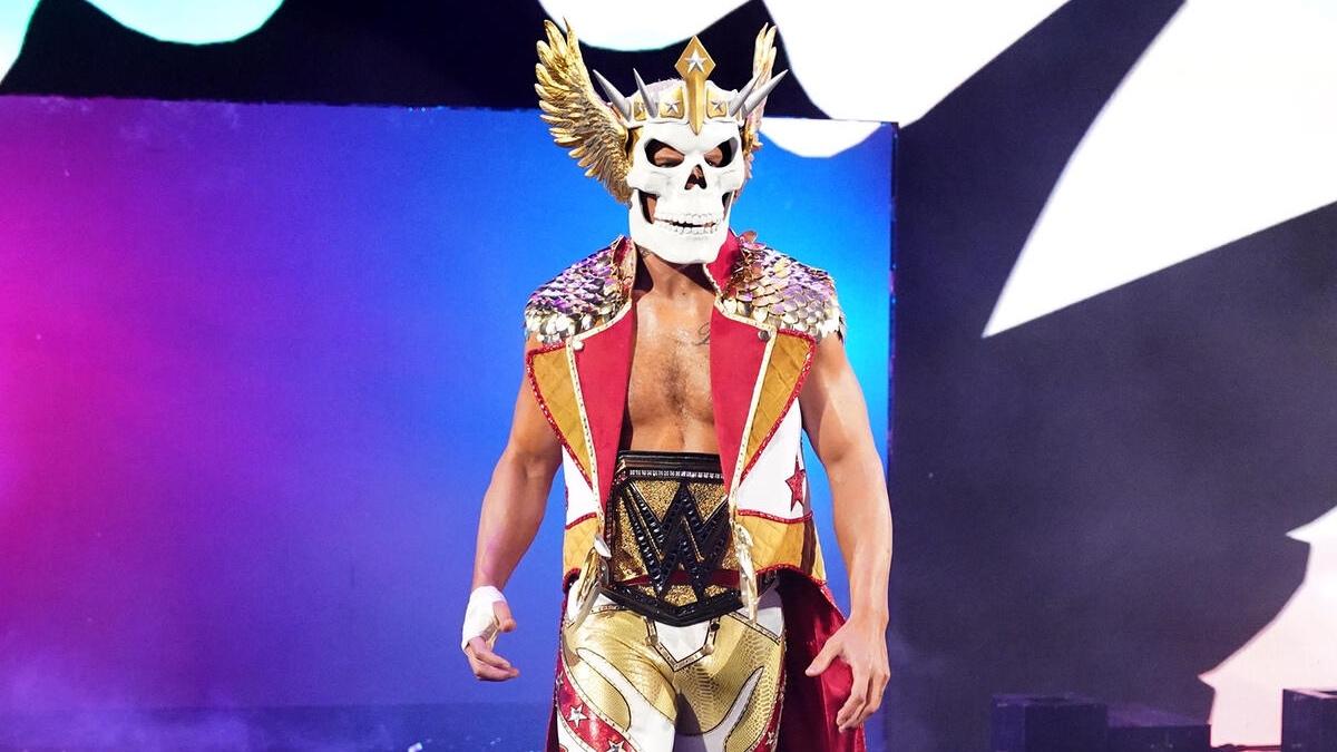 Cody Rhodes in a skull mask and ornate costume with the gold WWE Title belt onstage