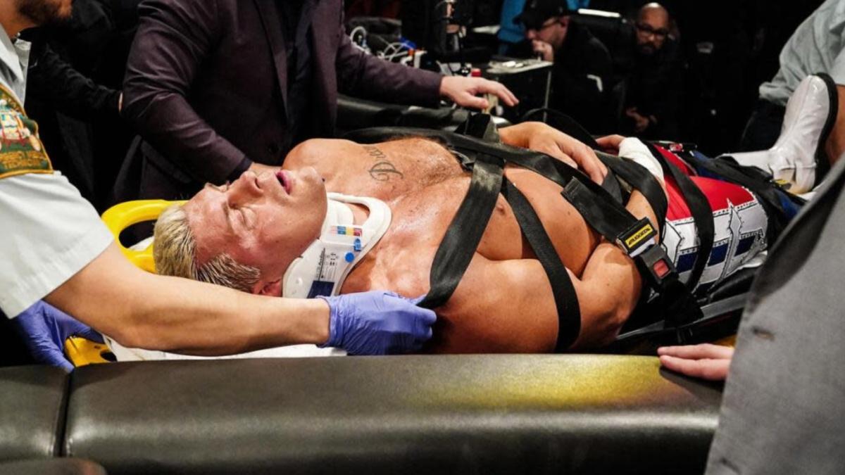 Cody Rhodes lying on a stretcher wearing a neck brace 