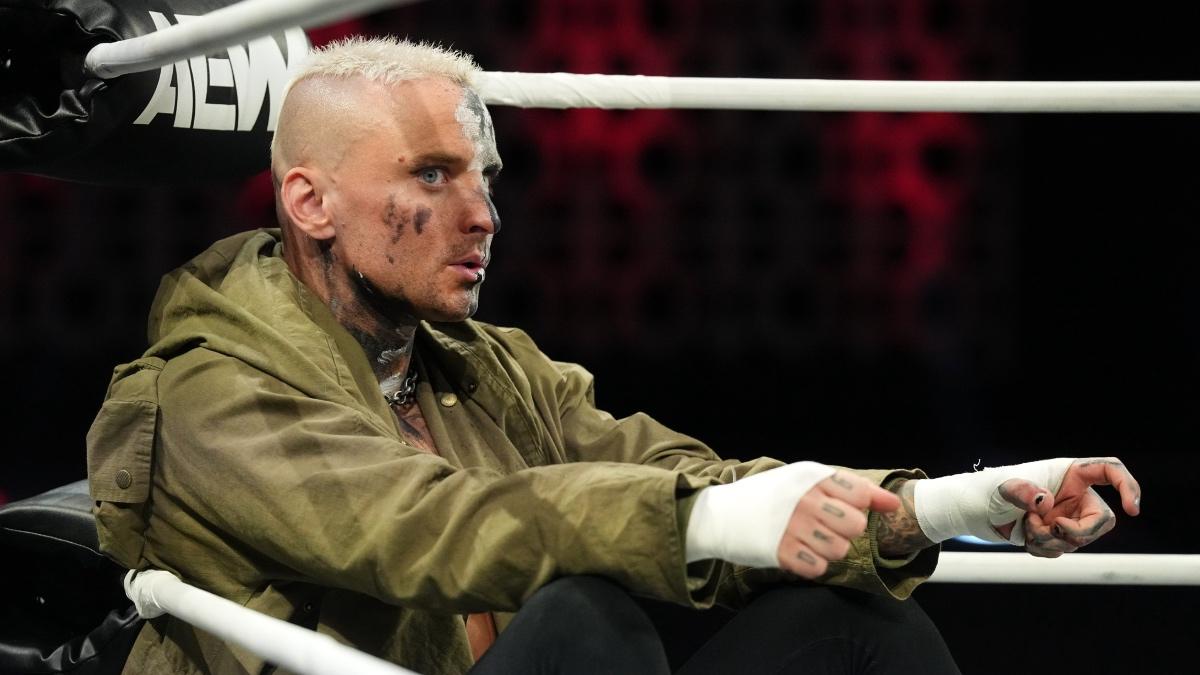 Darby Allin sitting in corner of pro wrestling ring wearing a green jacket