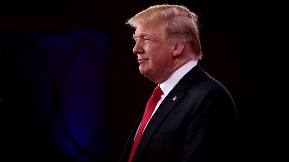 Donald Trump from the side with a red tie and blue suit