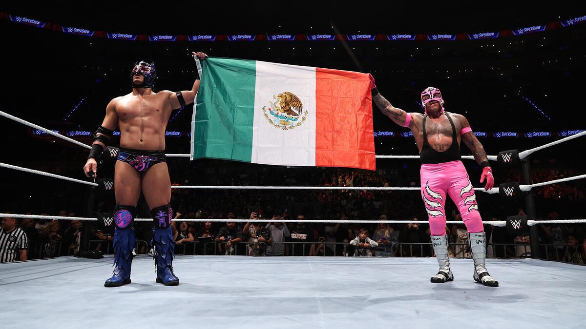 Rey Mysterio and Dragon Lee hold a Mexican flag in the middle of the ring following a match in the country