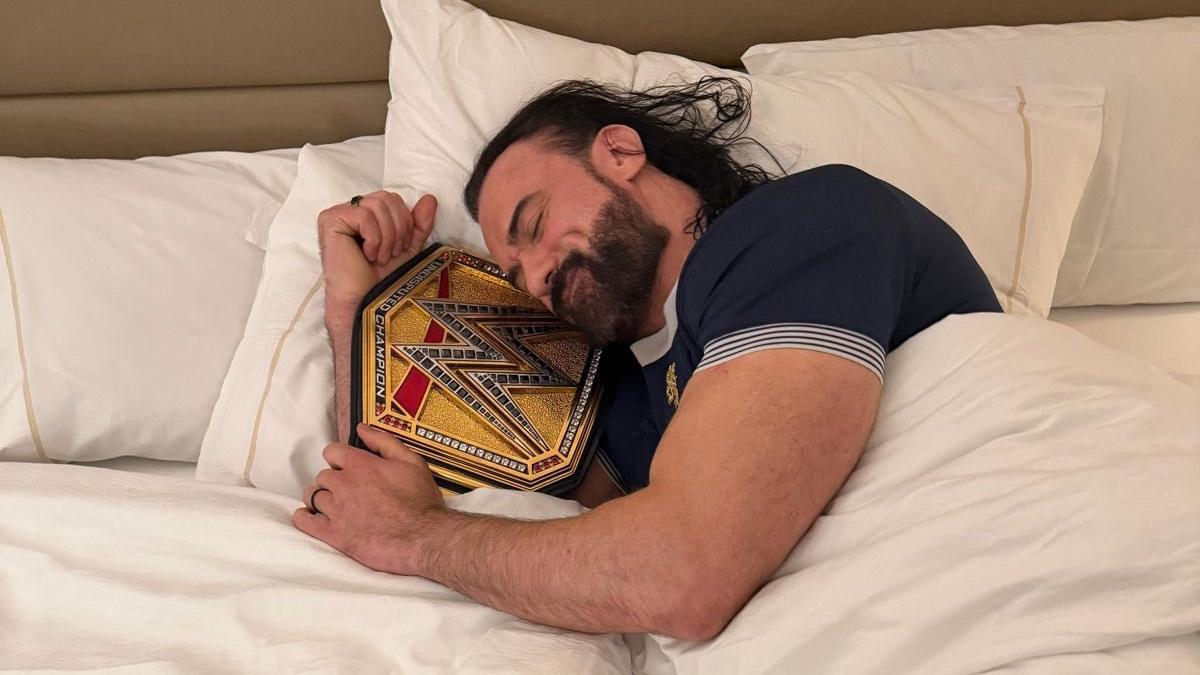 Drew McIntyre sleeping in a hotel bed while holding the Undisputed WWE Title