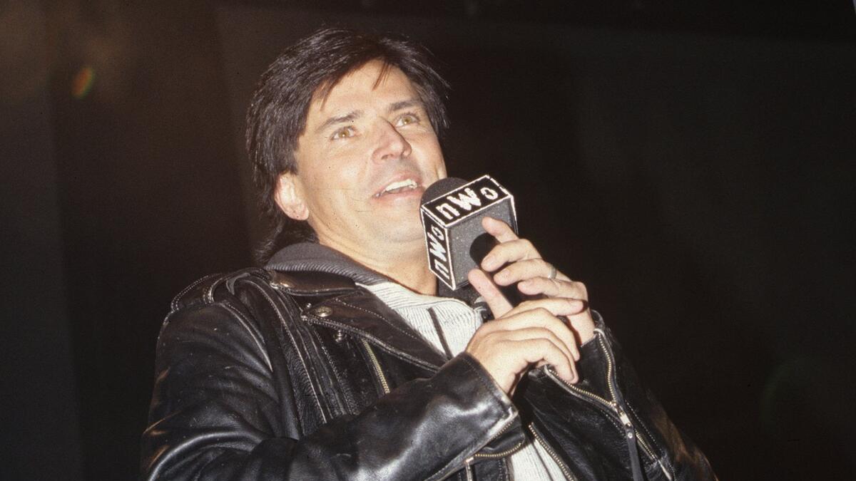 Eric Bischoff wearing a leather jacket holding an NWO microphone