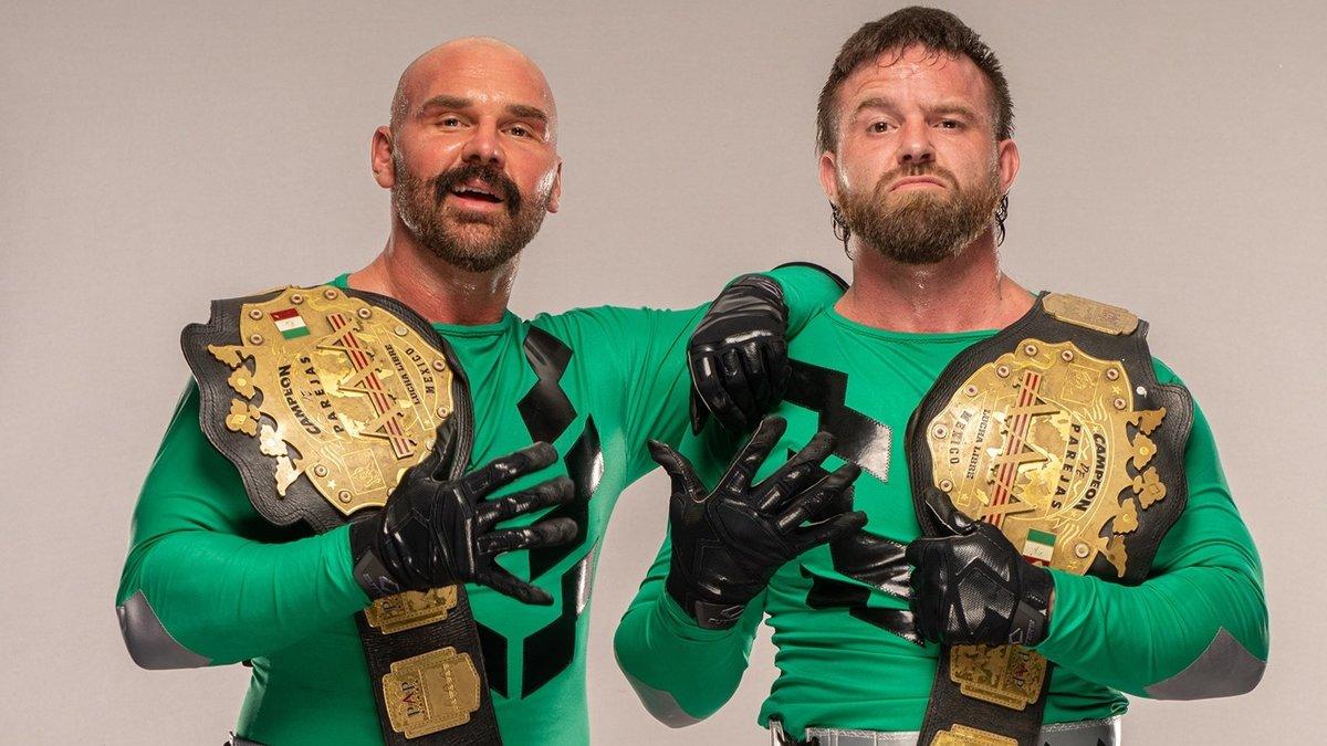 FTR in green body suits pose with the AAA World Tag Team Title belts
