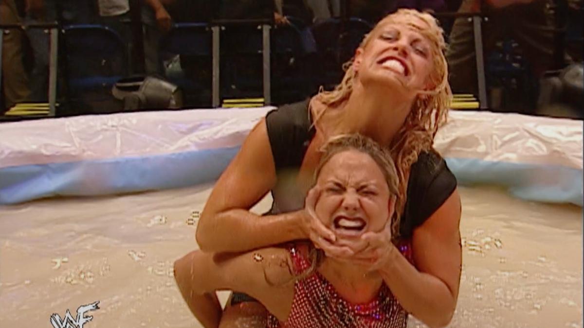 Trish Stratus applying a Camel Clutch to Stacy Keibler as they wrestle in a pool of gravy on a November 2001 episode of WWE SmackDown 