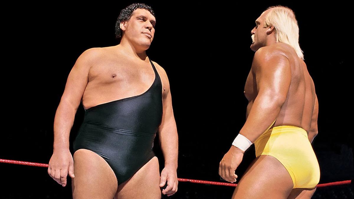 Andre the Giant and Hulk Hogan staring at each other inside a wrestling ring