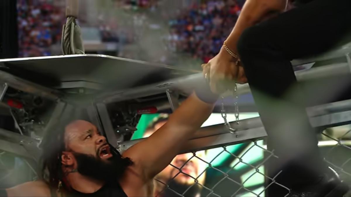 Jacob Fatu with his arm handcuffed to the cage looking despondent 