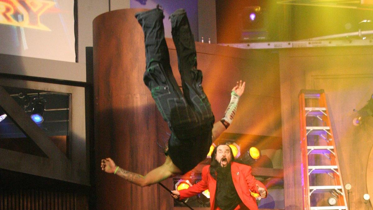 Jeff Hardy hitting a Swanton from the stage through a table as Father James Mitchell watches on in shock at TNA Bound For Glory 2005