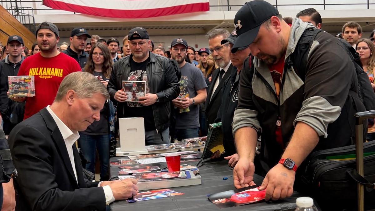 John Laurinaitis signing at Big Time Wrestling while surrounded by AI'd humans