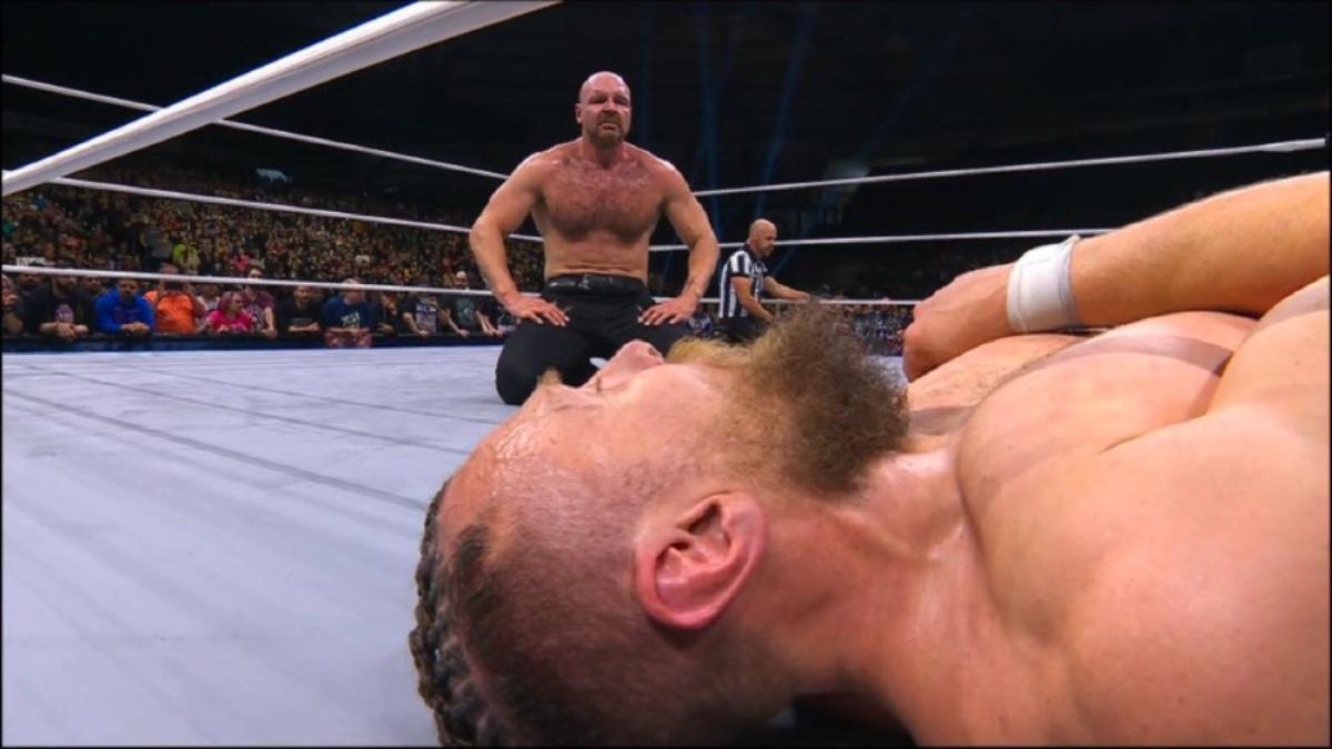 Jon Moxley staring at Bryan Danielson who is down on the mat