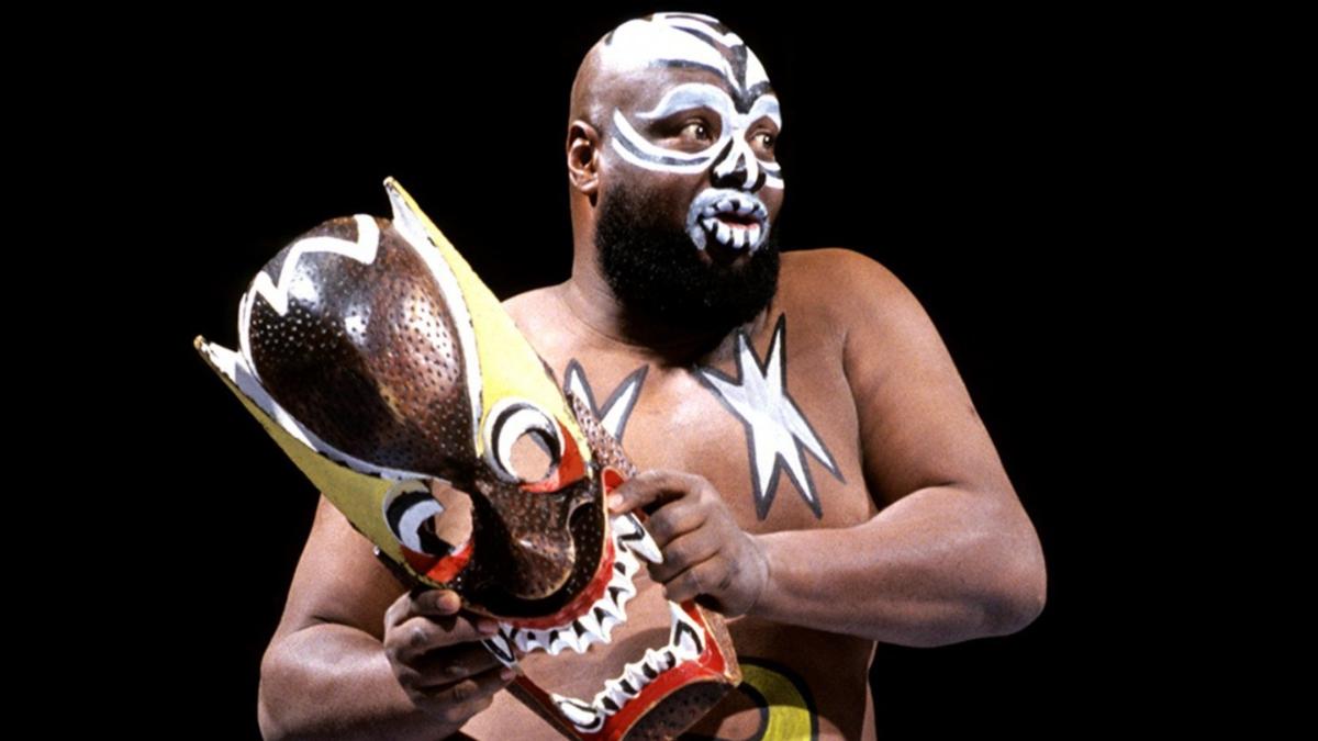 Kamala in a wrestling ring holding his oversized wooden entrance mask