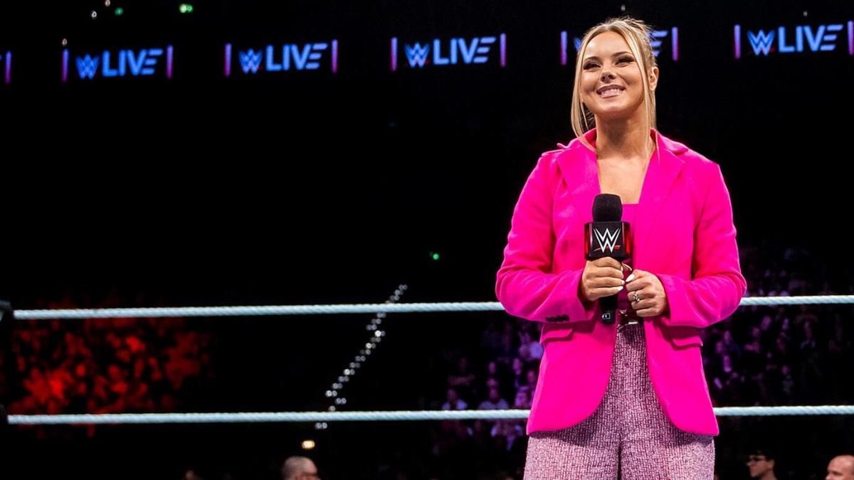 Kelly Kincaid standing in the WWE ring wearing a pink jacket