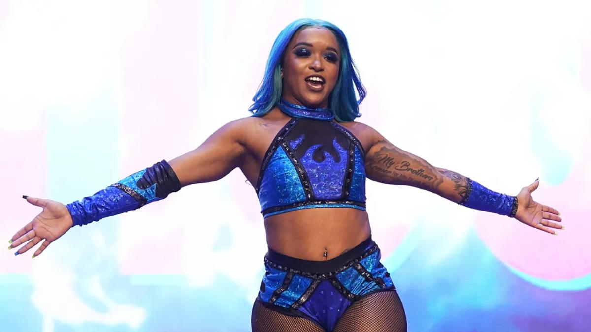 Kiera Hogan smiling with arms outstretched on an entrance ramp