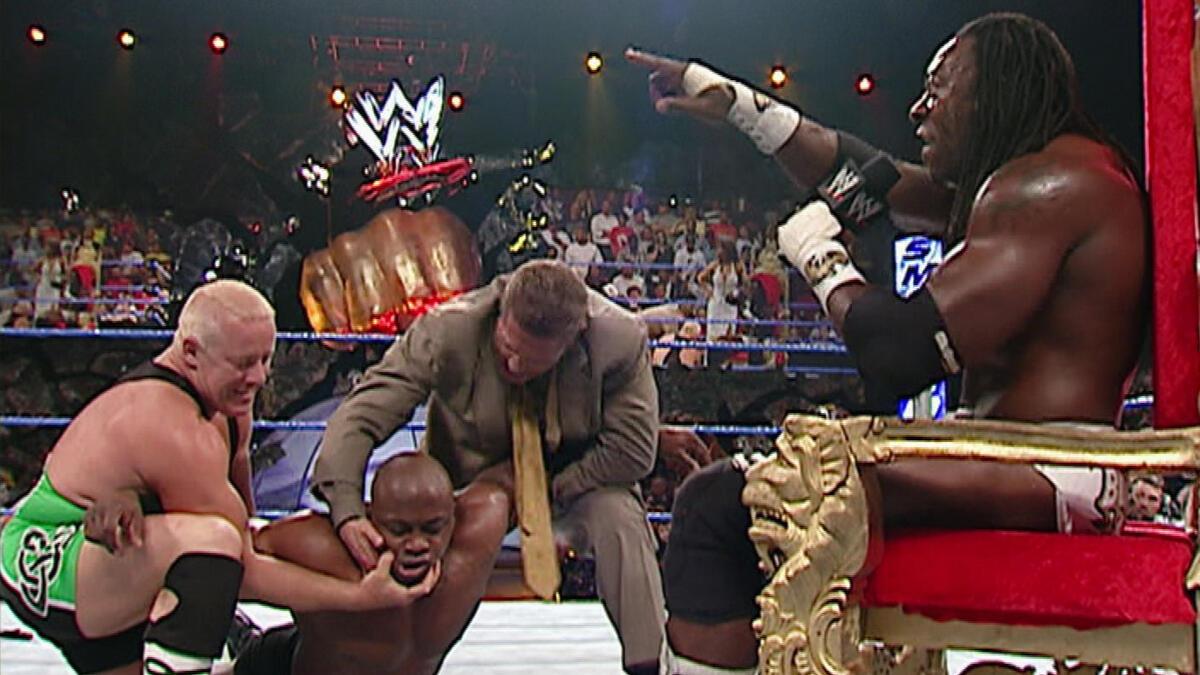 William Regal and Finlay holding down King Booker