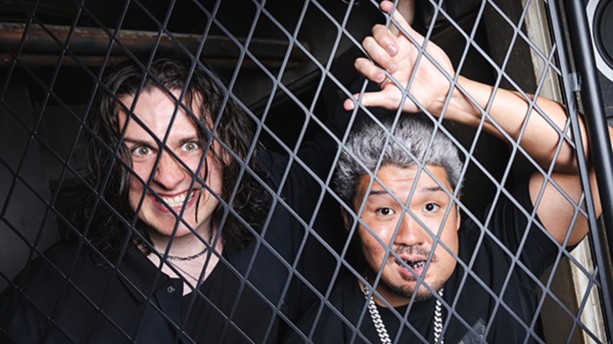 Knockout Brothers of Oskar Leube on the left and Yuto-Ice on the right looking through a mesh fence