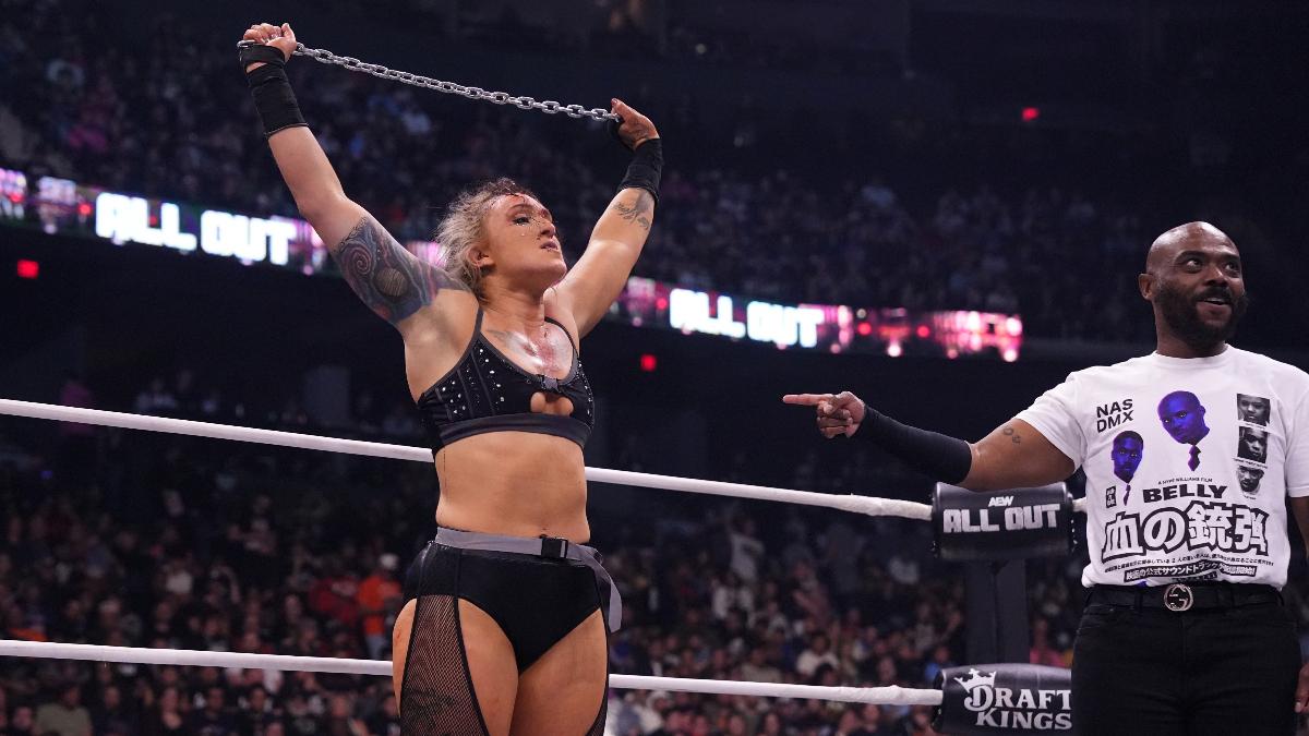 Kris Statlander holds a chain aloft in an AEW wrestling ring, with Stokely Hathaway pointing at them, in front of an audience.