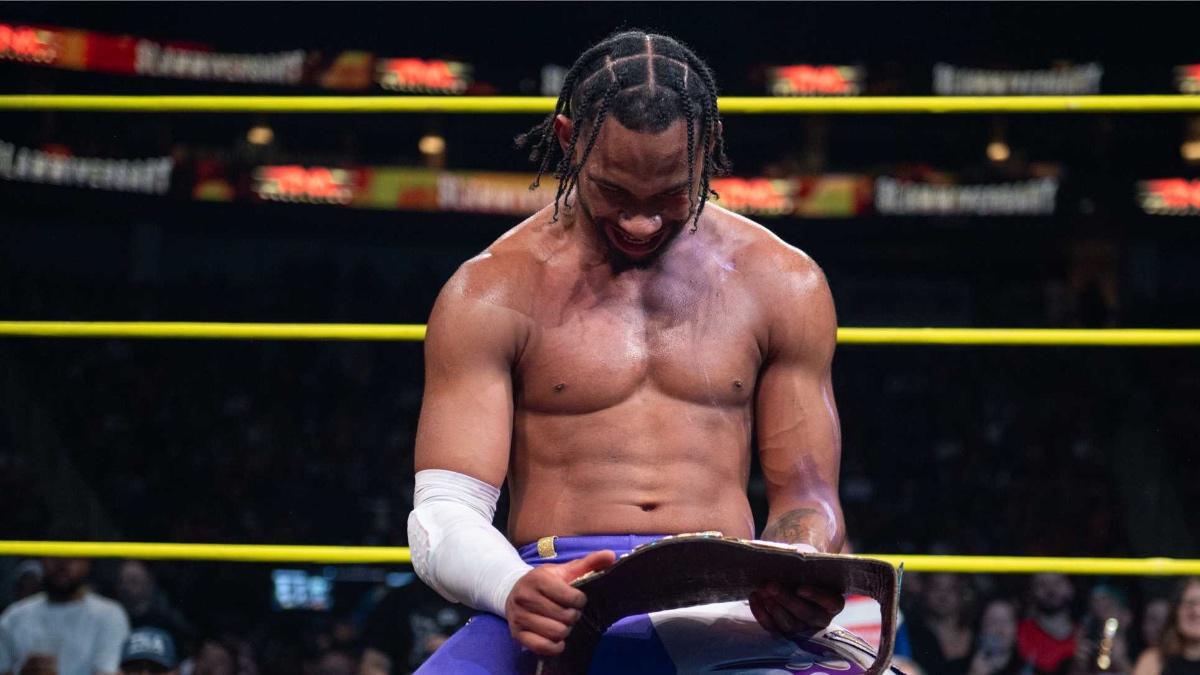 Leon Slater on his knees in the ring holding the X-Division Title at TNA Slammiversary