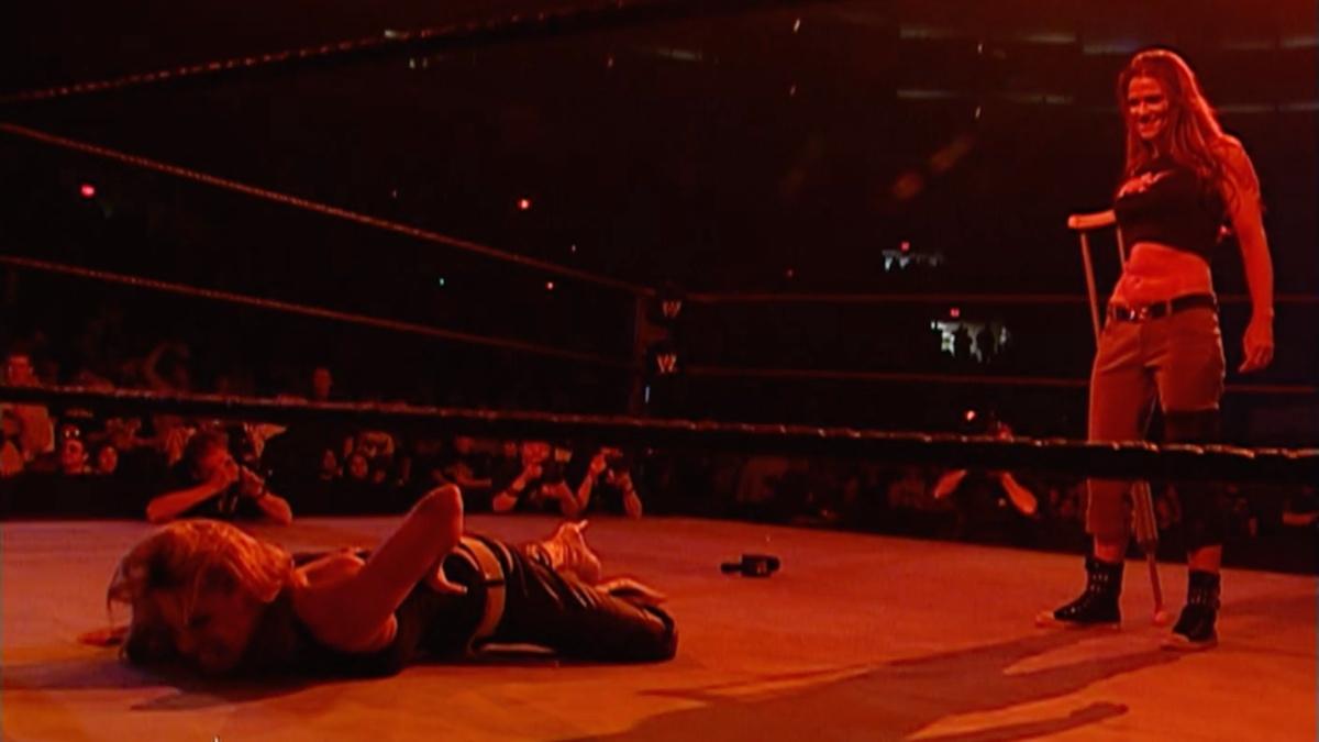 Lita standing next to Trish Stratus, who his lay down as the ring is bathed in a red glow on WWE Raw