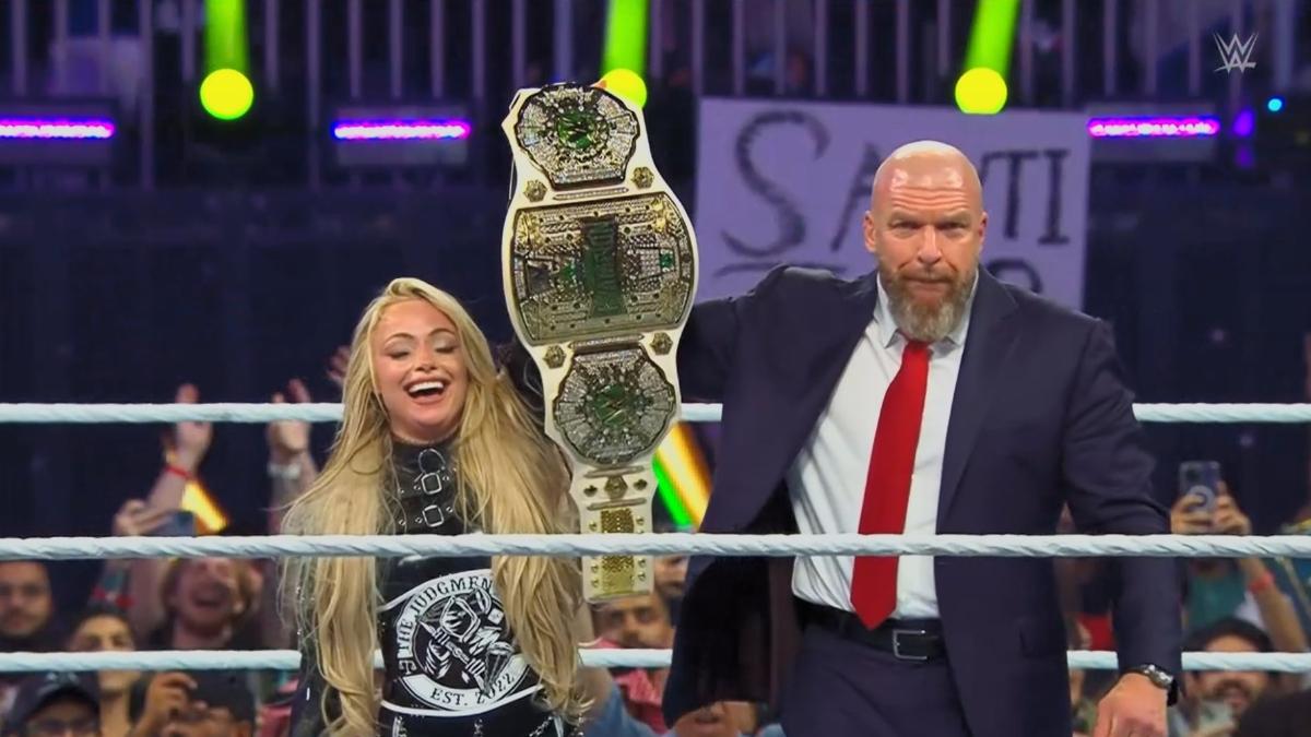 Liv Morgan celebrates in-ring with  a suited Triple H as she hold up the Crown Jewel Championship