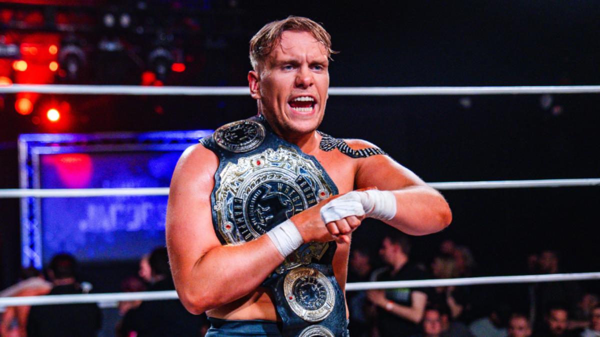 Luke Jacobs snarls with his wrist up and the PROGRESS World Championship over his shoulder