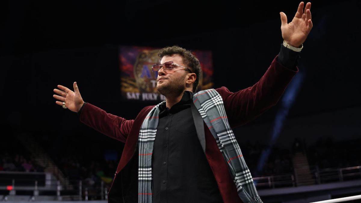 MJF in a velvet jacket and sunglasses with his arms outstretched