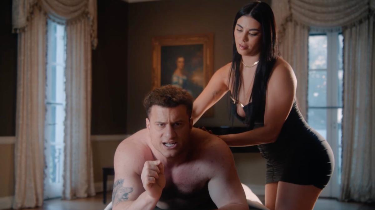 MJF lay on a massage table being massaged by a masseuse in a black dress