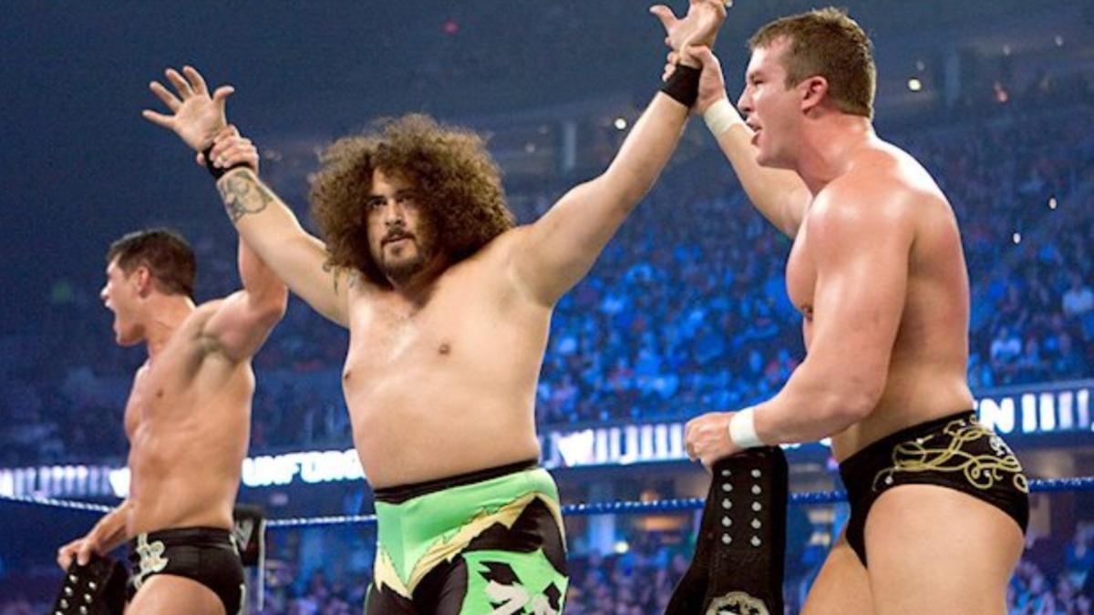 Manu getting his hands raised by Cody Rhodes and Ted DiBiase in a WWE ring