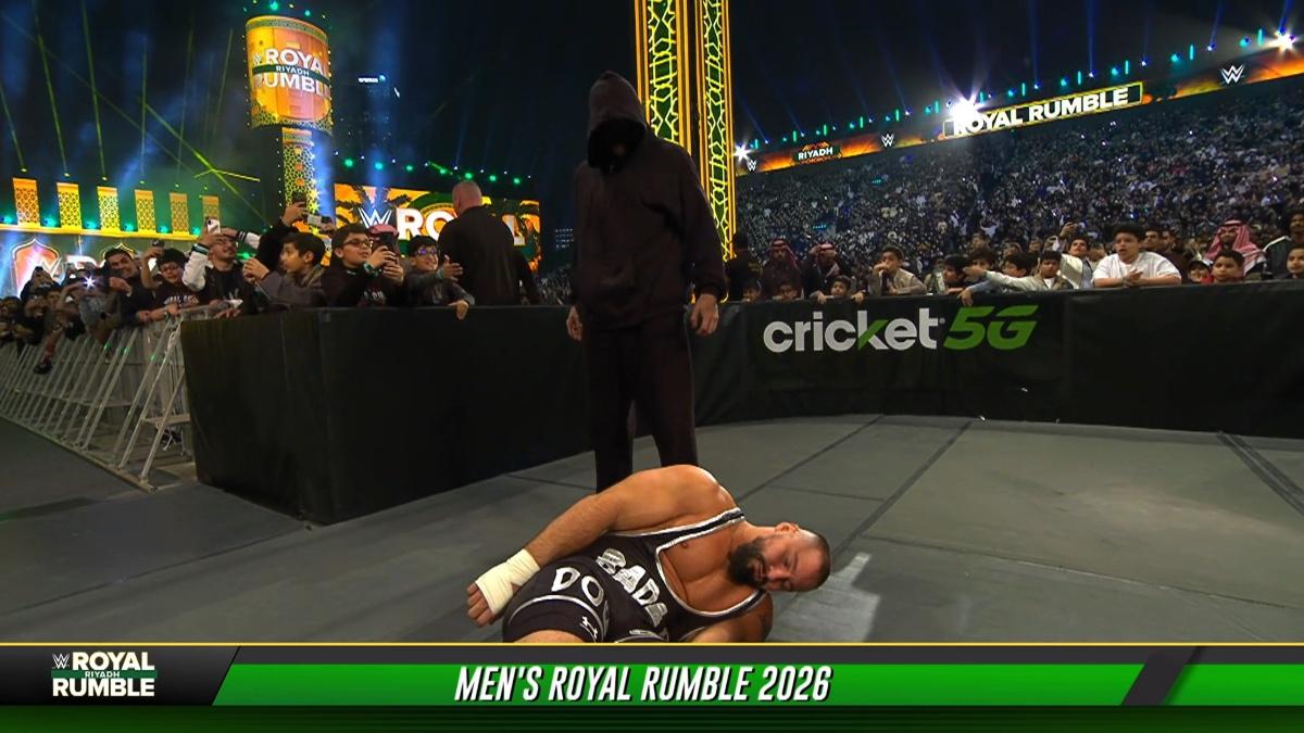 Masked Man standing over a groggy Bron Breakker on the outside of the ring at WWE Royal Rumble 2026